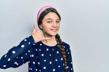 Young brunette girl wearing elegant look smiling doing phone gesture with hand and fingers like talking on the telephone. communicating concepts.