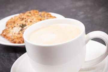 Cup of coffee with milk and fresh baked oatmeal cookies with honey and healthy seeds. Delicious crunchy dessert