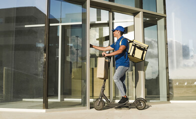 African delivery man doing fast food delivery with thermal backpack and electric scooter while ringing the doorbell - Focus on rider guy face