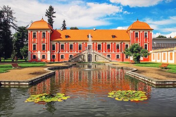 A front view to the beautiful castle with red facade and a pond in front at Ostrov, Czech republic