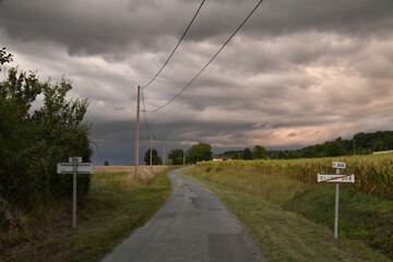 Fototapeta na wymiar Lumière du soleil couchant sur les nuages d'orages au dessus des champs au bourg de Champagne au Périgord Vert