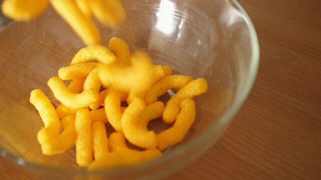 pouring cheese crisps chips snacks into a bowl slow motion