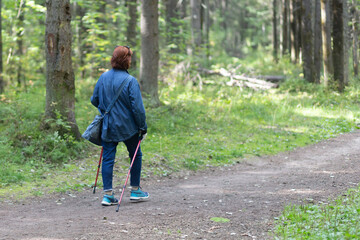 Nordic walking. A woman is engaged in Nordic walking in the park.