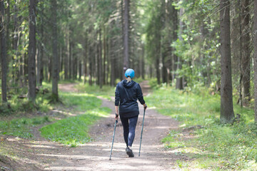 Nordic walking. A woman is engaged in Nordic walking in the park.