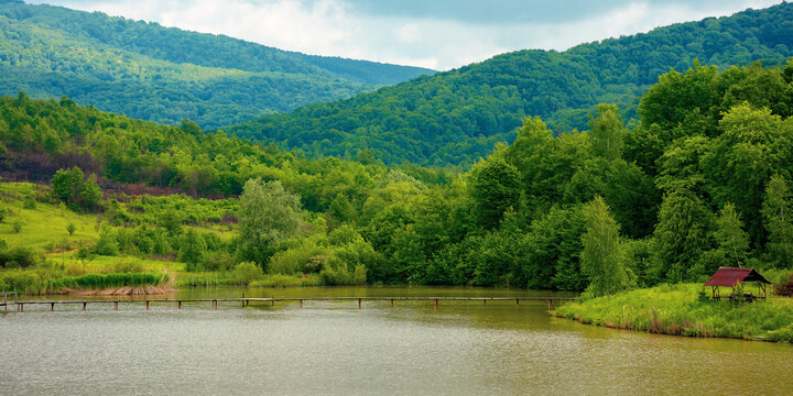 lake among mountain landscape in spring. beautiful countryside scenery with forest on the shore. clouds on the sky