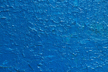 The texture of blue paint. The cracked surface of the wall is painted blue.