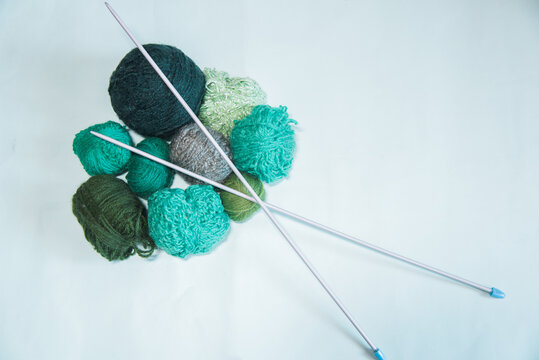 Ovillos de lana verde de diferentes tama&ntilde;os con unas agujas de tejer sobre fondo blanco. Crochet, ganchillo. Bolas de hilo. Madejas.