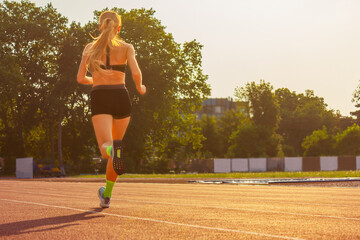 young woman in sportswear runs through the stadium, rear view. sports training and exercise....