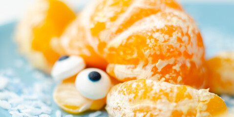 Fruit turtles, a snack made of fresh parts of mandarins served in the shape of water turtles on a blue plate