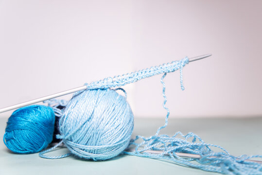 Ovillos de lana azul sobre un fondo blanco. Agujas de tejer con un proyecto incompleto e hilo desordenado. Crochet, ganchillo. Bolas de hilo. Madeja