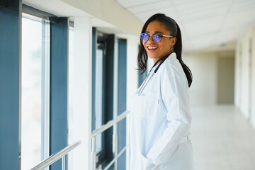 portrait of friendly, smiling confident female healthcare professional with lab coat, arms crossed holding glasses. Isolated hospital clinic background.