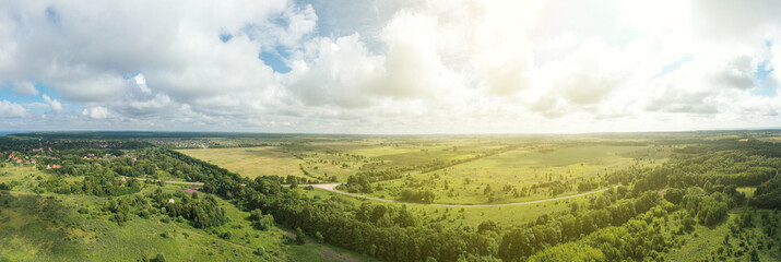 Fototapeta na wymiar Asphalt road through green summer field and forest near farmland. Aerial panoram