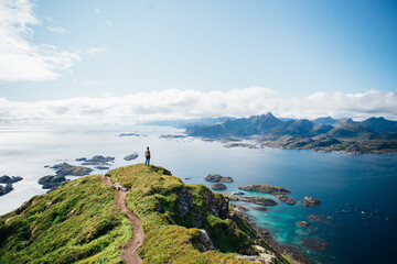 Amazing epic shot of young man hiker stand on top of mountain after long difficult hike in Lofoten...