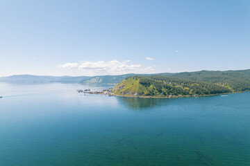Lake Baikal is a marvelous blue jewel framed by scenic mountains and forests. Epic cinematic aerial view Lake Baikal. Aerial view of blue lake and green forests.
