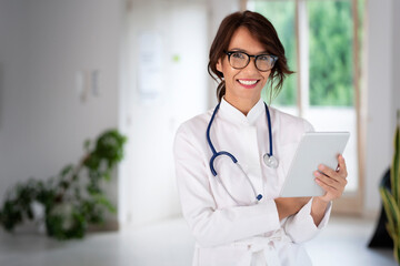 Attractive female doctor portrait while holding tablet in her hand and working at hospital