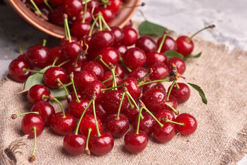 Bowl with red cherry on sackcloth background, top view