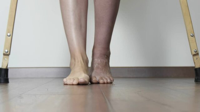 A woman after a broken leg to learn to walk. Rehabilitation after removal of plaster bandage. A woman walks on crutches.