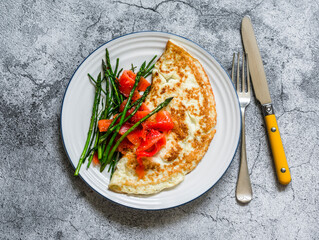 Delicious breakfast, brunch omelet with asparagus and smoked salmon on a gray background, top view