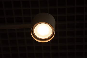 a round white lamp on the ceiling on in the evening, a lamp on in the dark as a background, lamp