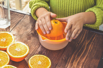 the girl child makes freshly squeezed orange juice on a manual juicer