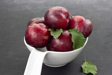 Plums on a white cup and black background