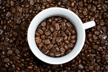 Cup of coffee full of coffee beans.