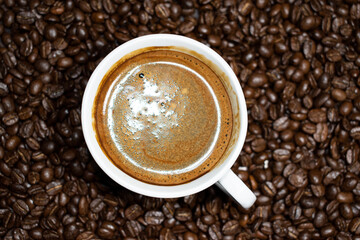 Coffee cup top view on roasted coffee beans background