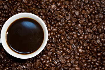 Coffee cup top view on roasted coffee beans background