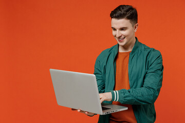 Smiling charismatic happy charming fun young brunet man 20s wears red t-shirt green jacket hold use...
