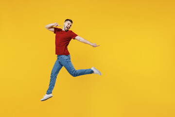 Fototapeta na wymiar Full length fun young man wear red t-shirt casual clothes jump high point index finger aside on workspace area isolated on plain yellow color wall background studio portrait People lifestyle concept
