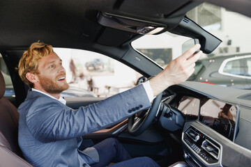 Side view man driver male cabdriver in classic grey suit drive car hold wheel touch mirror in traffic jam look camera show thumb up test auto want buy new automobile vehicle Sale transport concept