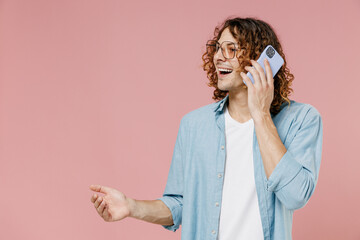 Young smiling happy man 20s with long curly hair in blue shirt white t-shirt glasses talk speak on...