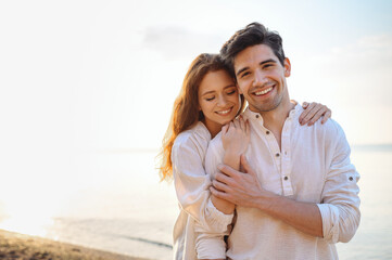 Romantic charming sunlit smiling happy young couple two friends family man woman in casual clothes hug each other at sunrise over sea beach ocean outdoor exotic seaside in summer day sunset evening.