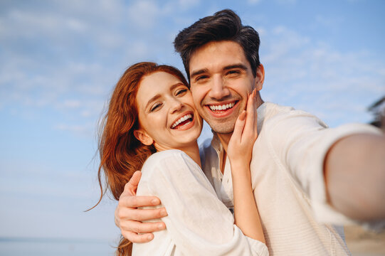 Close up satisfied happy young couple two family man woman wear white clothes hug each other do selfie shot pov on mobile phone at sunrise over sea beach outdoor seaside in summer day sunset evening