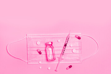 Syringe with medicine from a glass bottle, a protective medical mask on pink background. Vaccination against influenza, covid 19, measles, coronavirus disease. Vaccination and immunization concept
