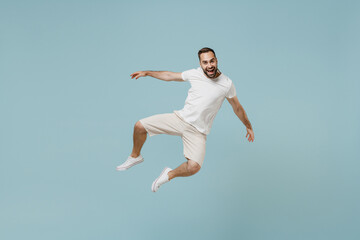 Full length young overjoyed excited smiling happy caucasian man 20s wear casual white t-shirt jump high like flying leaning back isolated on plain pastel light blue color background studio portrait