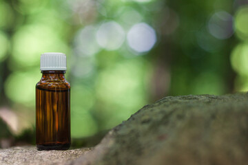 Essential oil in bottle on stone. Bokeh nature background, copy space. Natural Medicine. Blur nature background.