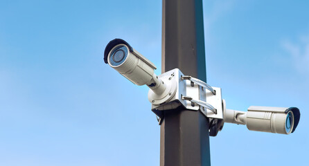 Surveillance, dual cctv video camera on the pole with sky background. Security Camera, CCTV. Public watching, space for text