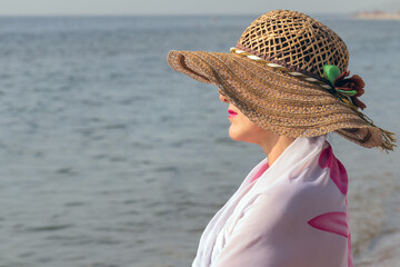 female portrait in profile, middle-aged woman in a straw hat against the background of the sea