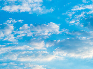 Blue sky background with white clouds at sunset.