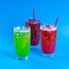 red and green fresh cocktails smoothie jusice in glass with ice on blue background. vitamin drink detox