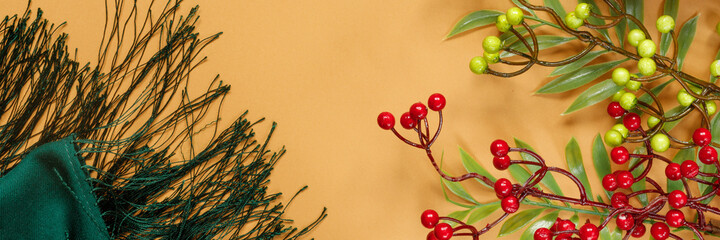 Bouquet of autumn leaves and branches of mountain ash with  green woolen scarf on orange background. Cozy home concept. Creative banner.