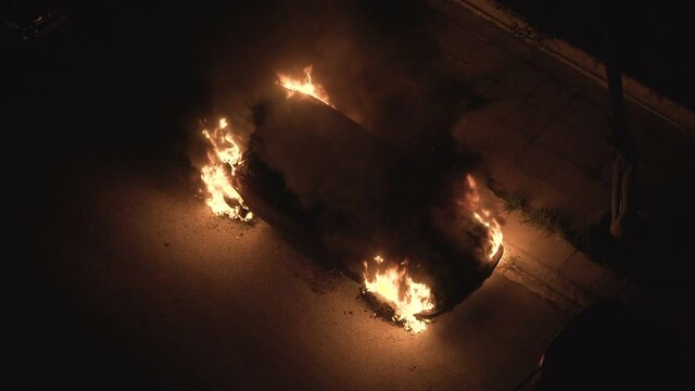 burning car set in fire at night on a city street 