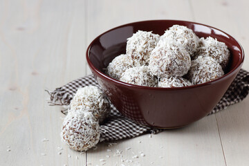 Vegan balls with dates, peanut butter and coconut on dark moody background, healthy protein...