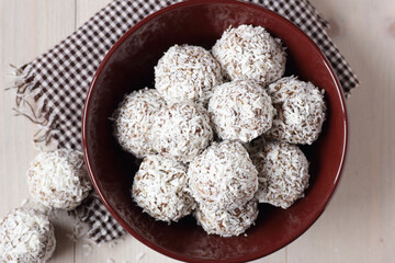 Vegan balls with dates, peanut butter and coconut on white wooden background, overhead from above top view, healthy protein homemade dessert for christmas holidays, closeup, copy space, vertical