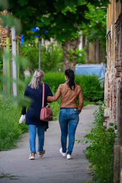 Two Women Walking On The Street. Real People. View From Behind