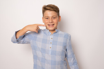 Fototapeta premium Child pointing with finger teeth and mouth. Caucasian young teenager, isolated on white background. Concept of good teeth care. Dental health concept.