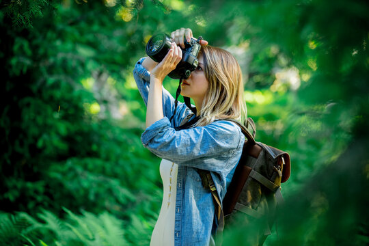 young girl with a camera and a backpack in the park