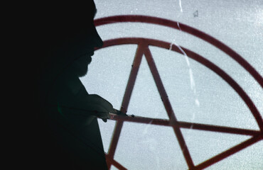 Silhouette of artisan drawing star on carpet canvas in dark workshop 