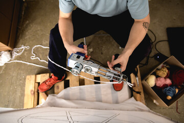 Top view of craftsman holding carpet tufting machine near canvas 